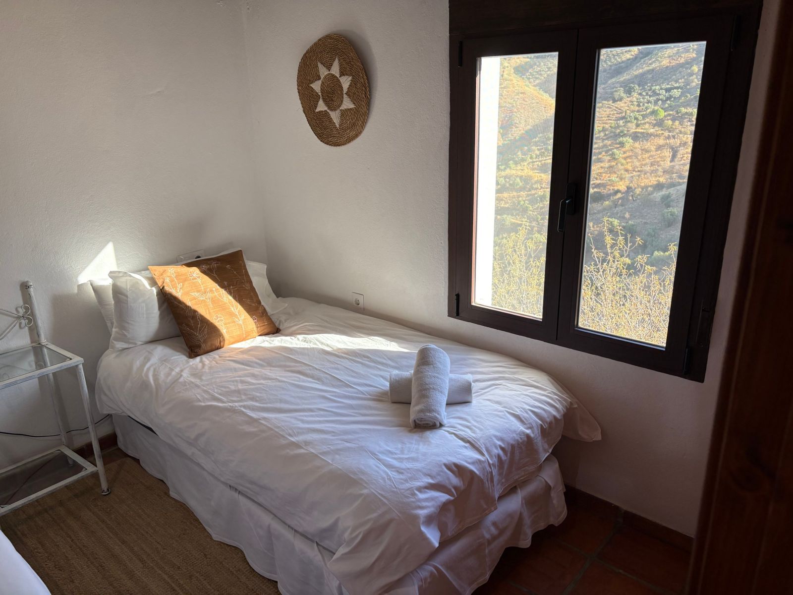 Sunlit bedroom with a window onto the hills