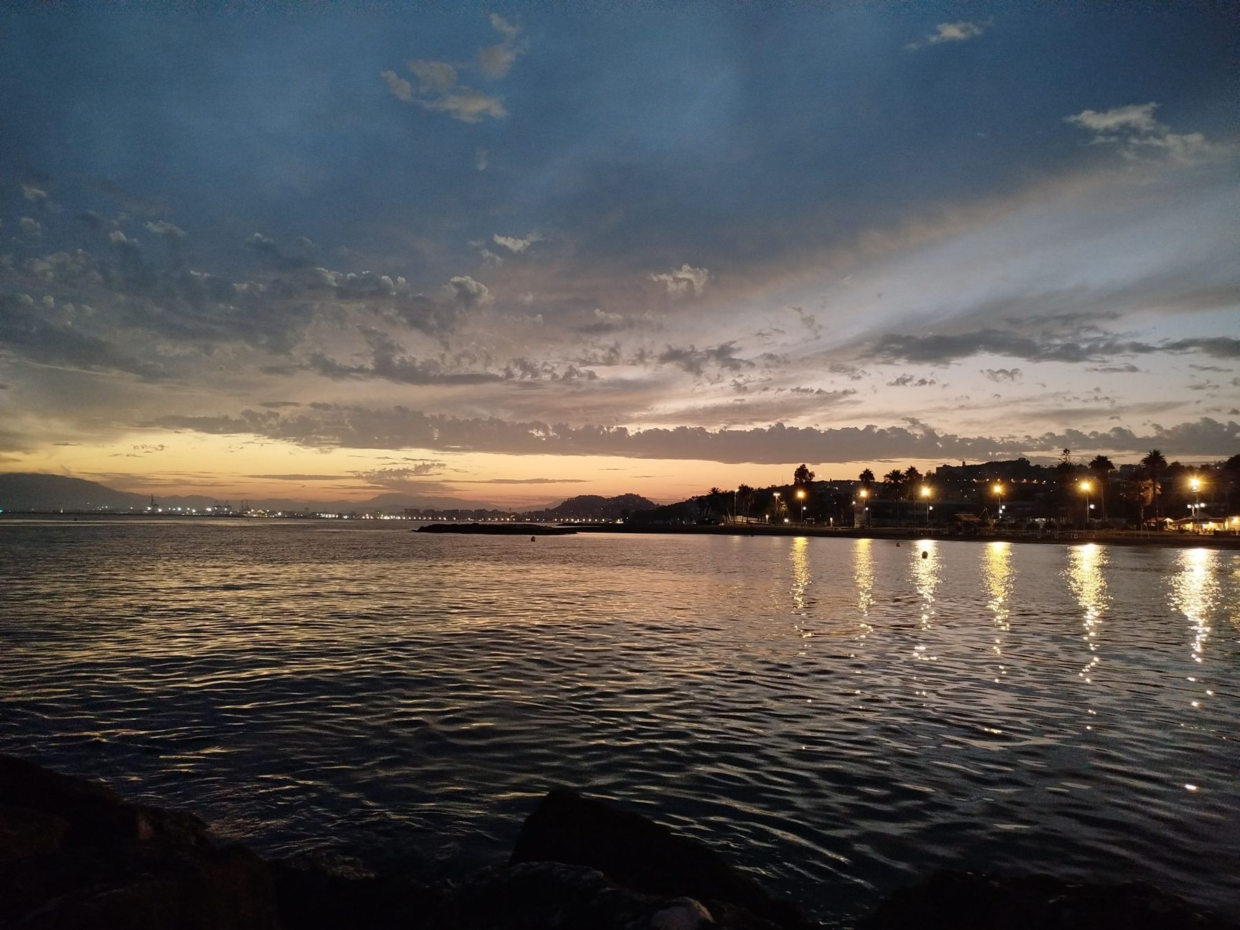 Dusk over the bay of Málaga, with the lights of the coast reflected in the water