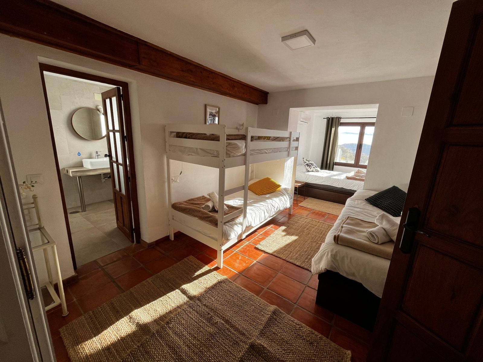 Bright room with two single beds and a bunk bed, with its own bathroom