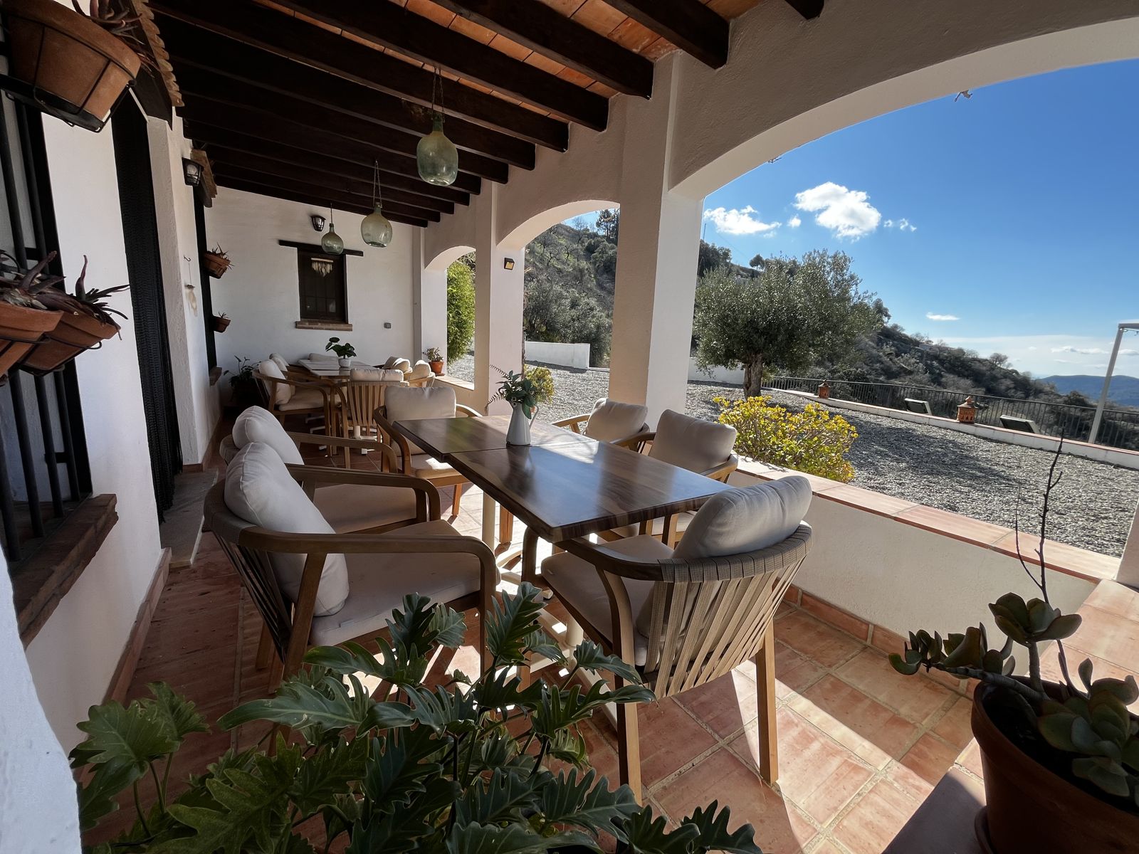 Covered porch with dining tables and valley views at Villa Trompetilla