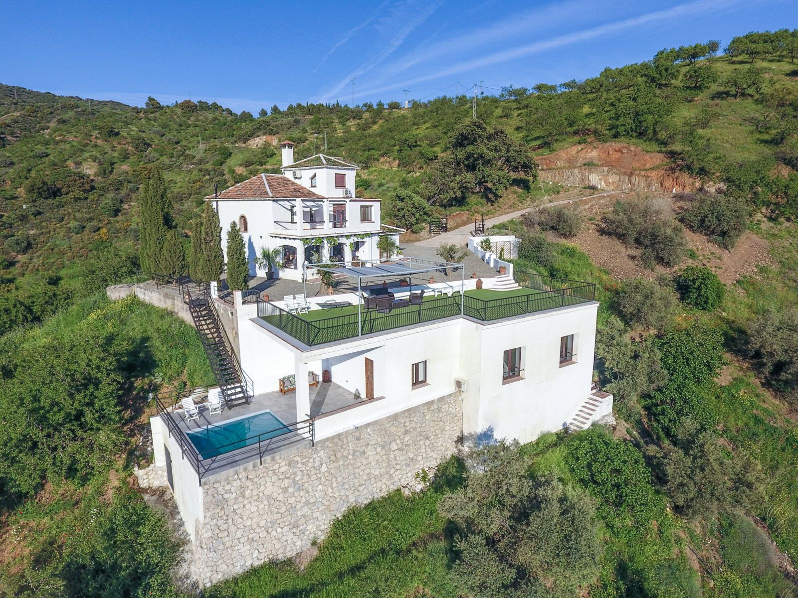 Aerial view of Villa Trompetilla and its terraces on a green hillside